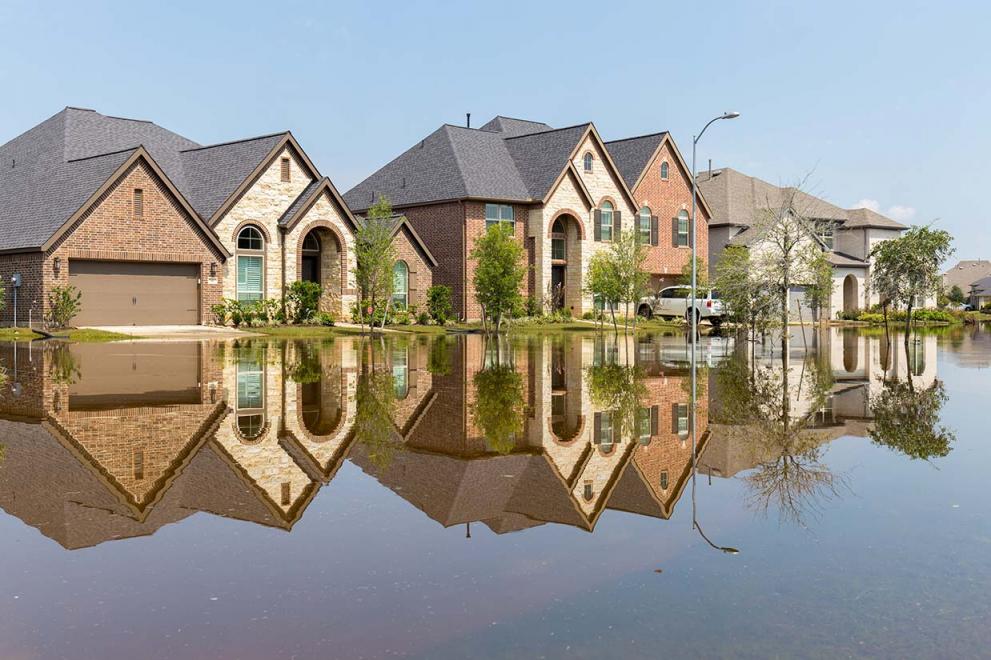 Flooded residential street after a storm, clear skies overhead
