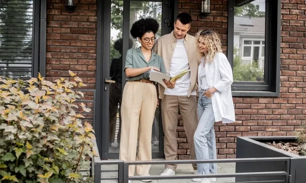 Insurance agent reviewing documents with couple on home's porch