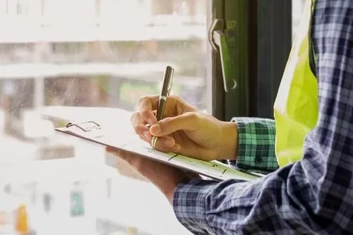 Contractor in hi-viz vest writing on clipboard