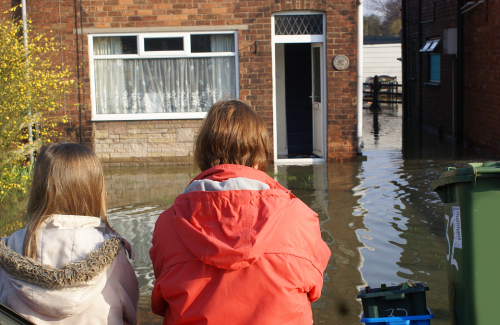 Kids standing in front of their flooded home