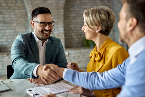 Three people meeting at a desk, shaking hands
