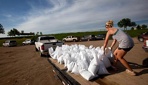 Woman moving sandbags from pallet into back of truck