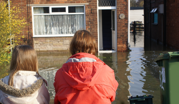 children viewing their flooded home
