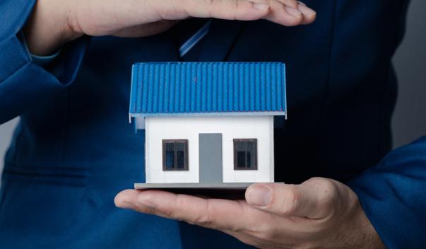 A model home with hands over and under it